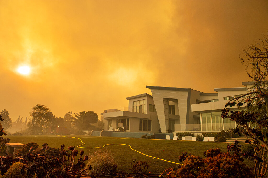 A single fire hose crosses artificial grass in the backyard of a house on Hidden Glen Lane after the Green Fire passed by in Yorba Linda, Calif., Monday, Oct. 26, 2020 (Leonard Ortiz/The Orange County Register via AP)