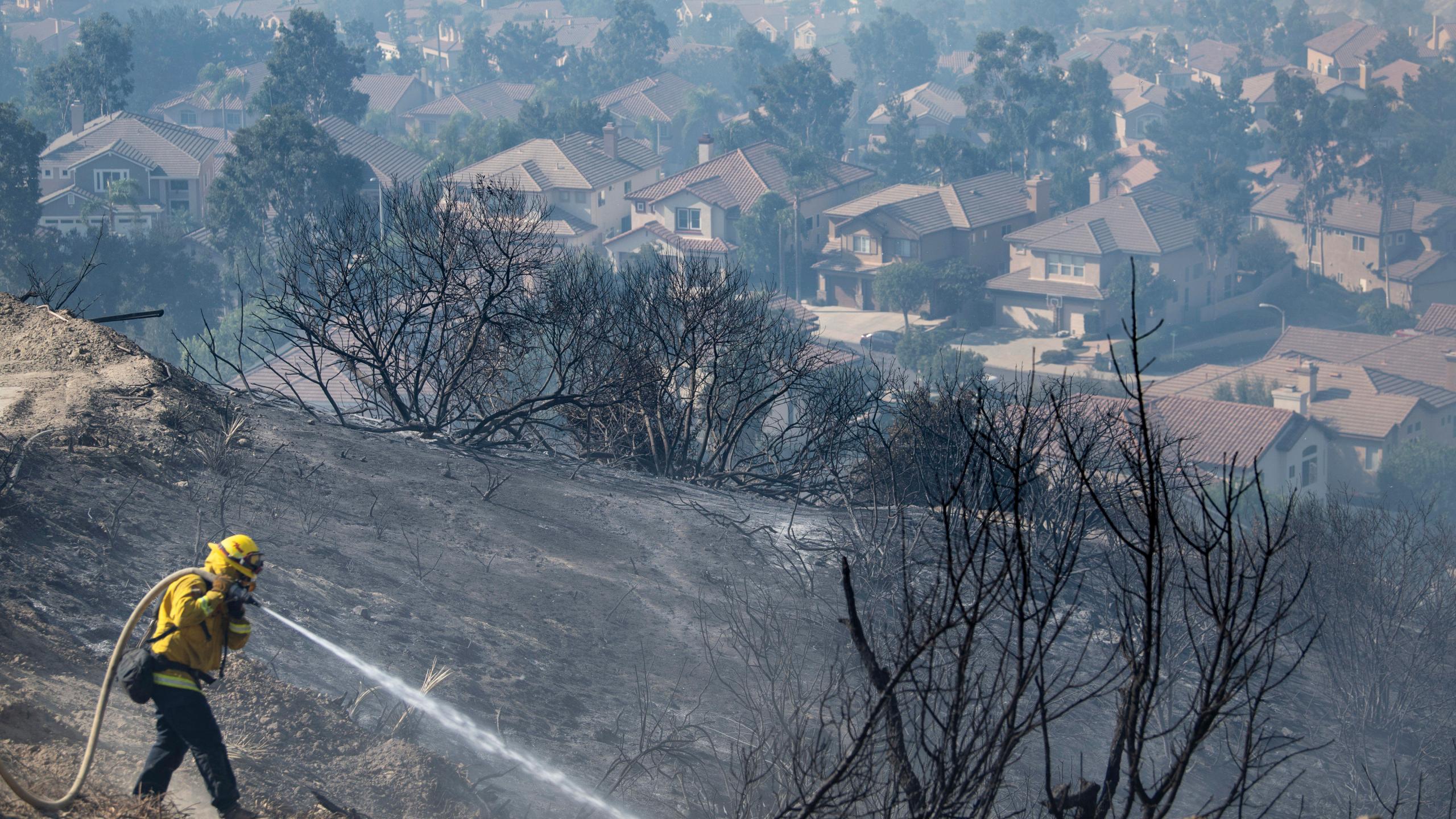 Firefighters work flames from the Silverado Fire atop a hill above homes in Foothill Ranch where a mandatory evacuation is in place on Tuesday, Oct. 27, 2020. (Mindy Schauer/The Orange County Register via AP)