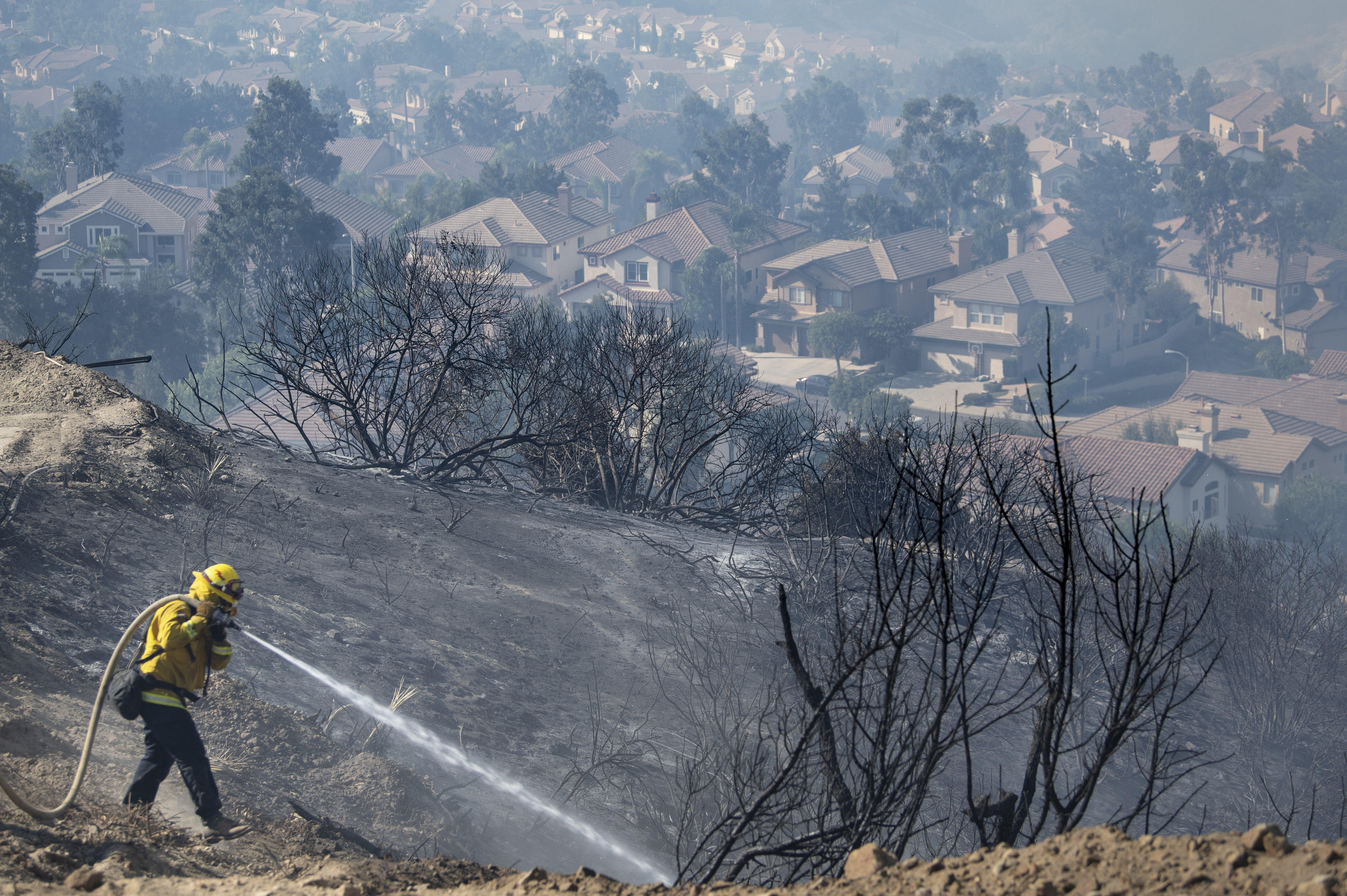 Firefighters work flames from the Silverado Fire atop a hill above homes in Foothill Ranch where a mandatory evacuation is in place on Tuesday, Oct. 27, 2020. (Mindy Schauer/The Orange County Register via AP)