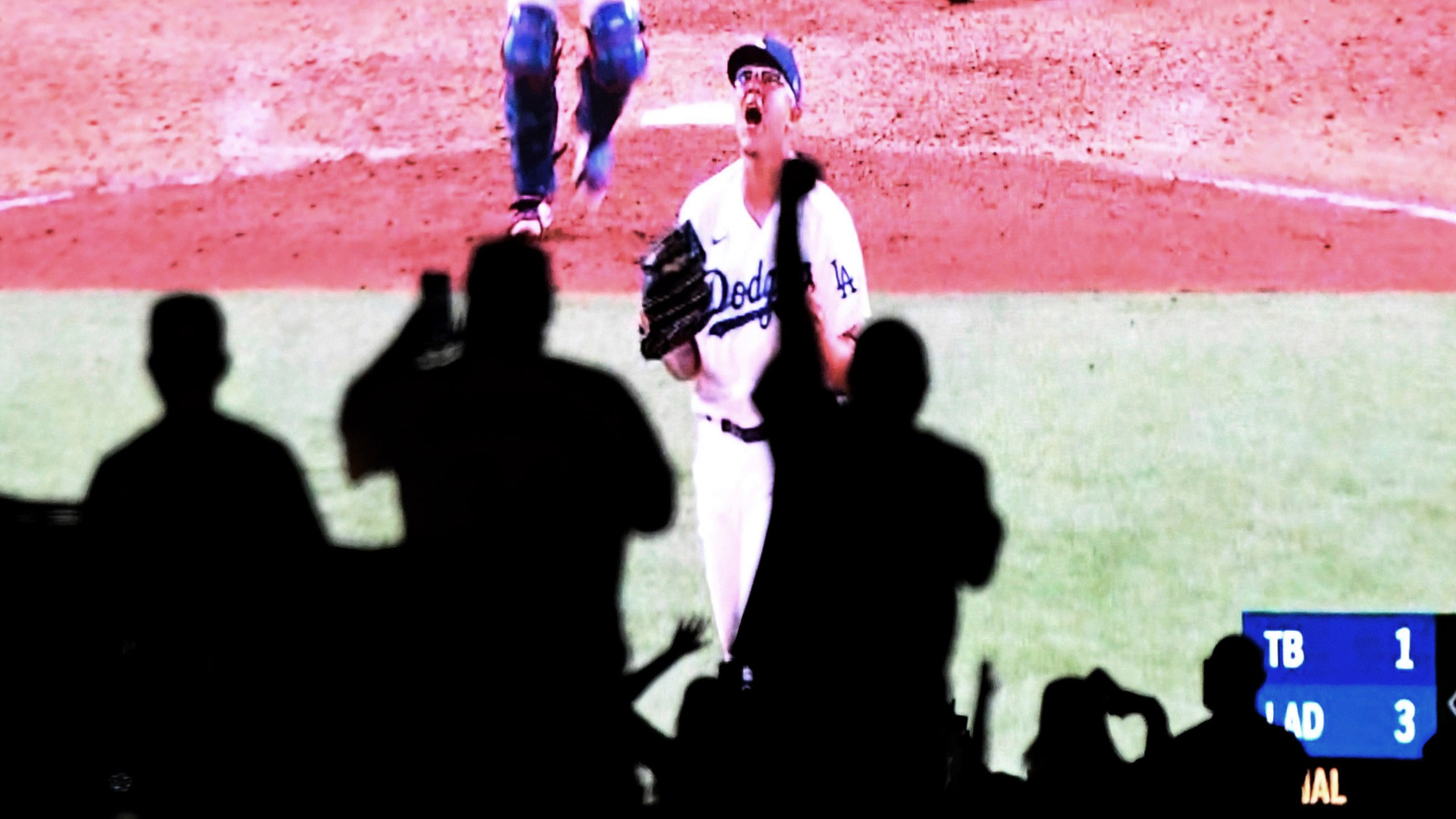 Julio Urías of the Los Angeles Dodgers reacts after the last out as fans celebrate from their cars in the parking lot at Dodger Stadium as they watch the national broadcast of the Los Angeles Dodgers defeating the Tampa Bay Rays 3-1 during game 6 to win the the 2020 MLB World Series on Oct. 27, 2020. (Keith Birmingham/The Orange County Register via Associated Press)