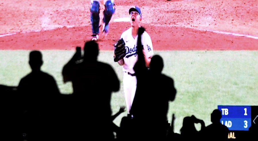 Julio Urías of the Los Angeles Dodgers reacts after the last out as fans celebrate from their cars in the parking lot at Dodger Stadium as they watch the national broadcast of the Los Angeles Dodgers defeating the Tampa Bay Rays 3-1 during game 6 to win the the 2020 MLB World Series on Oct. 27, 2020. (Keith Birmingham/The Orange County Register via Associated Press)