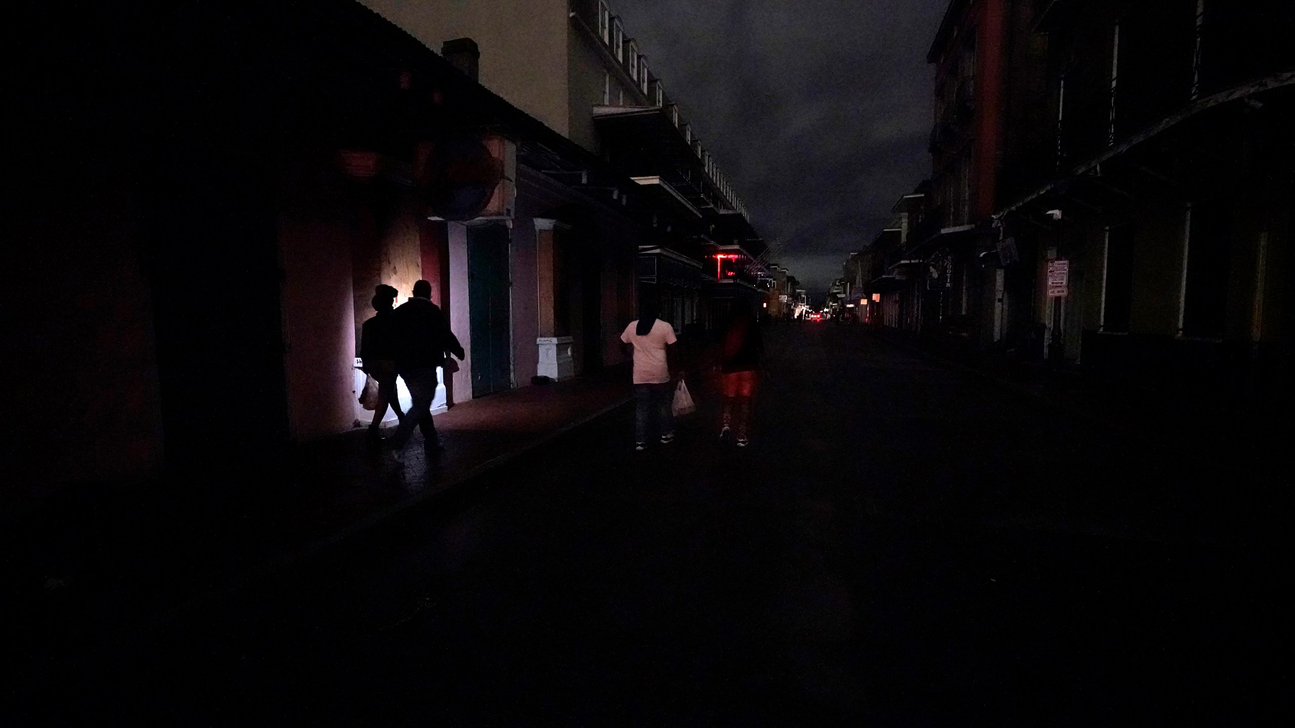 A darkened Bourbon Street is illuminated only by passers-by with lights and car headlights New Orleans' French Quarter on Oct. 28, 2020, after Hurricane Zeta passed through leaving much of the city and metro area without power. (Gerald Herbert / Associated Press)