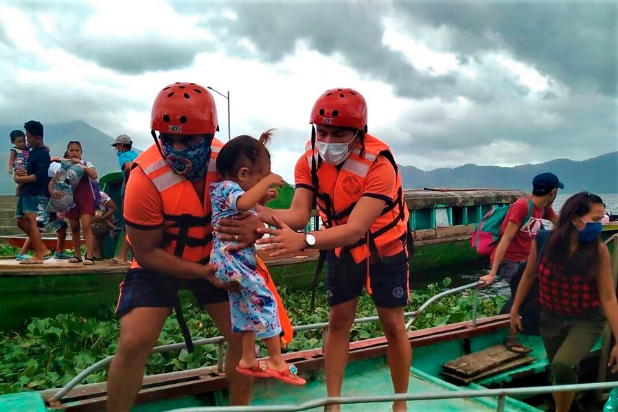 In this photo provided by the Philippine Coast Guard, members of the Philippine Coast Guard carry a child as they are evacuated to safer ground in Camarines Sur province, eastern Philippines on Saturday Oct. 31, 2020 as they prepare for typhoon Goni. (Philippine Coast Guard via AP)