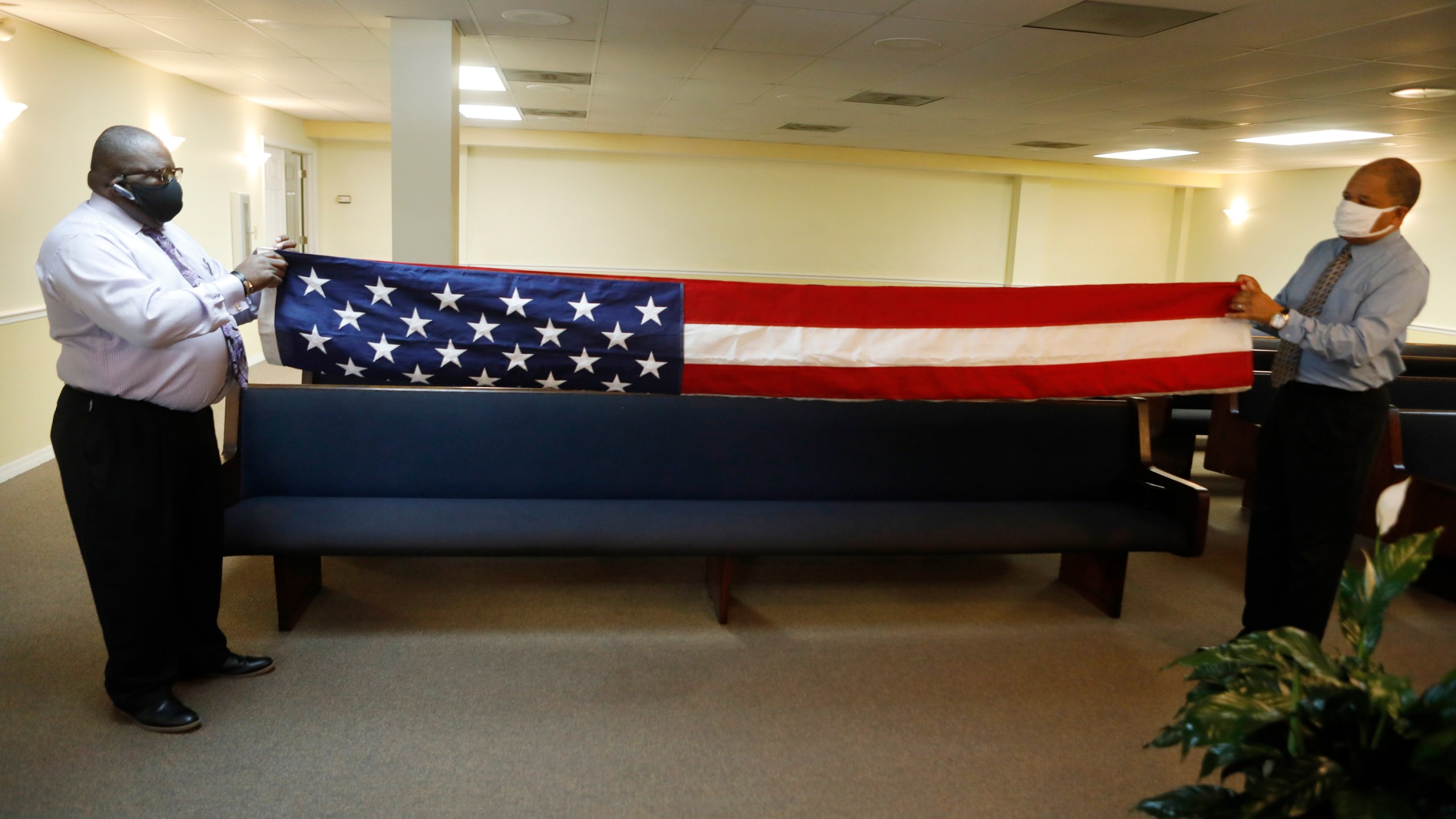 Robert Sturgis, left, an intern embalmer and Jeffrey Rhodes, the funeral home director, fold an American flag for a veteran who died of COVID-19 before his funeral at Ray Williams Funeral Home on Aug. 12, 2020 in Tampa, Florida. (Octavio Jones/Getty Images)