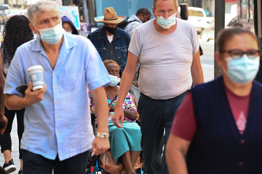 People wearing masks walk on a street in downtown Los Angeles on Oct. 2, 2020, amid the coronavirus COVID-19 pandemic. (ROBYN BECK/AFP via Getty Images)