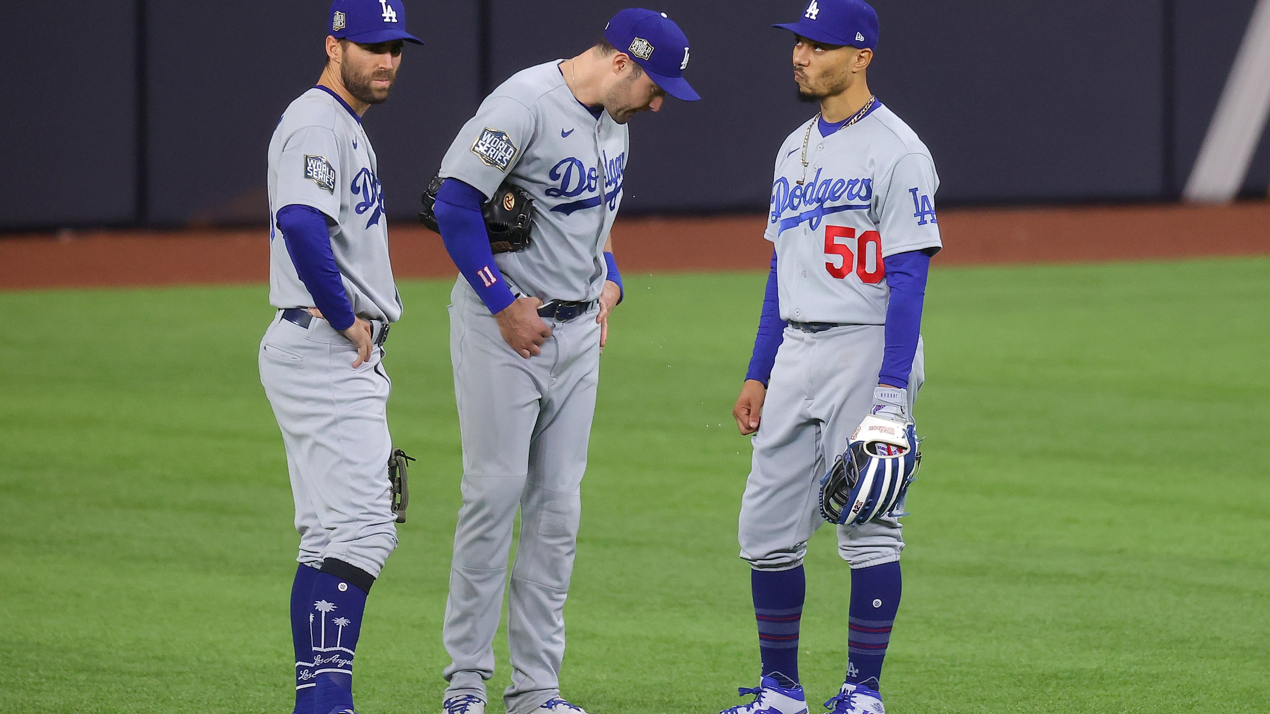 Chris Taylor, A.J. Pollock and Mookie Betts of the Los Angeles Dodgers talk during a pitching change against the Tampa Bay Rays during the seventh inning in Game Four of the 2020 MLB World Series at Globe Life Field on Oct. 24, 2020 in Arlington, Texas. (Ronald Martinez/Getty Images)