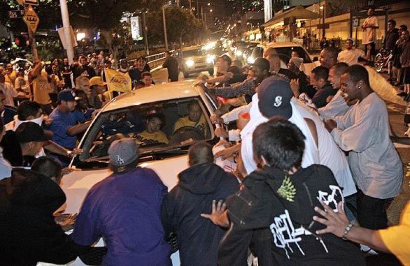 A group of people rock a car on Pico Boulevard amid celebrations of the Lakers title victory. (Gina Ferazzi / Los Angeles Times)