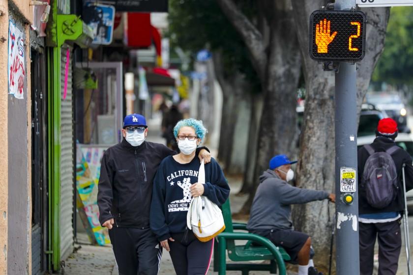 A couple walk down Cesar E. Chavez Boulevard near downtown Los Angeles.(Irfan Khan / Los Angeles Times)