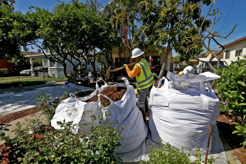 Workers remove topsoil from homes in Boyle Heights in 2015 as part of a state-led cleanup of lead contamination from thousands of properties surrounding the closed Exide Technologies battery recycling plant in Vernon.(Irfan Khan/Los Angeles Times)