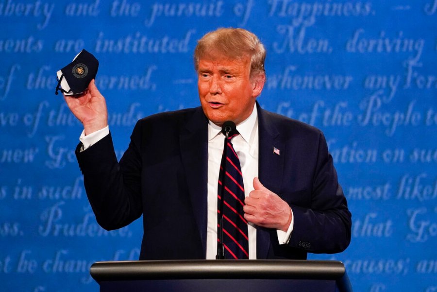 President Trump holds up his face mask during the first presidential debate at Case Western University and Cleveland Clinic, in Cleveland, Ohio. President Trump and first lady Melania Trump have tested positive for the coronavirus, the president tweeted early Friday. (AP Photo/Julio Cortez, File)