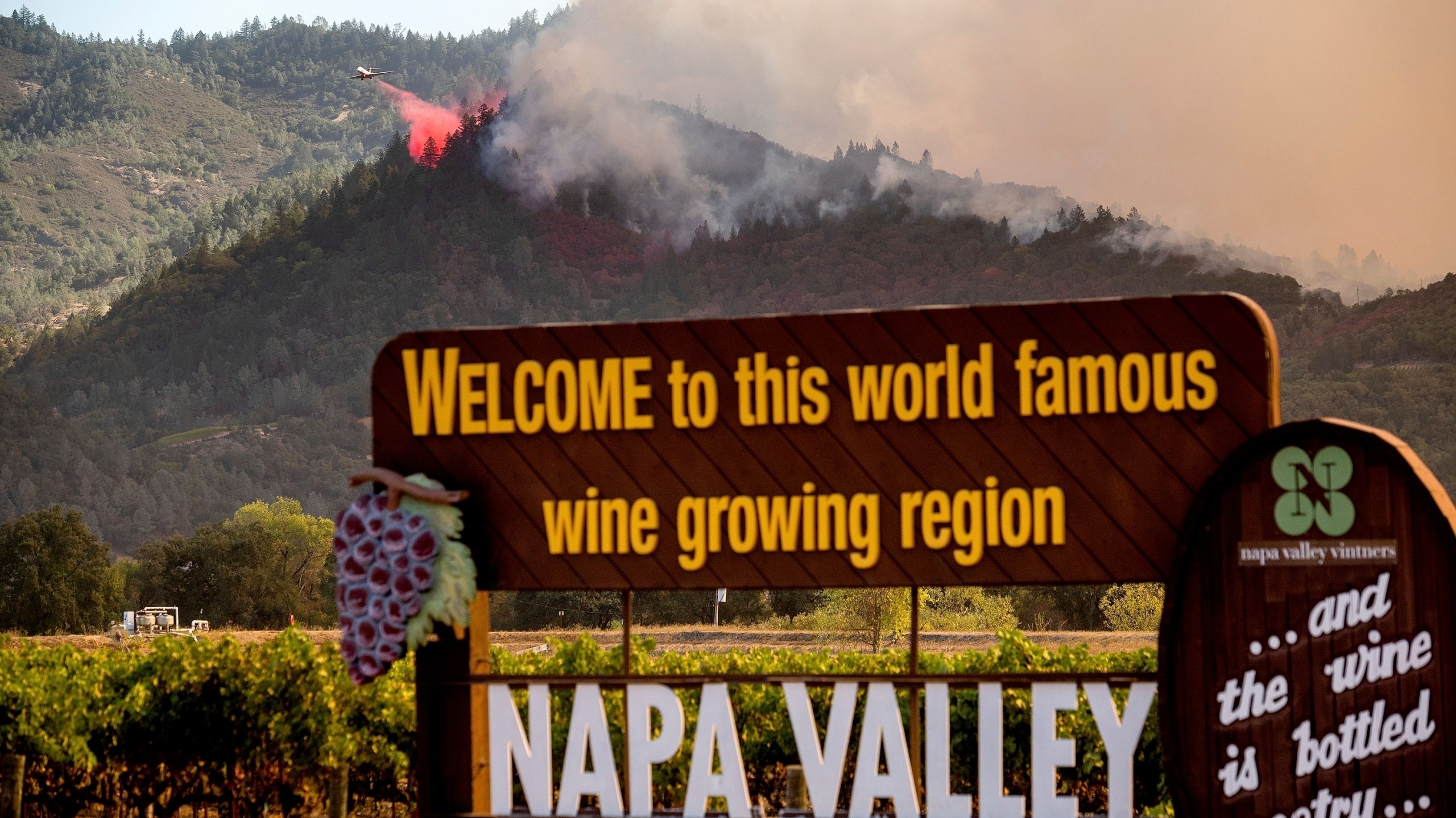 In this Sept. 27, 2020, file photo, an air tanker drops retardant on the Glass Fire burning in Calistoga, Calif. In three of the past four years, major wildfires driven by a changing climate have devastated parts of the world-class region, leaving little doubt that it's vulnerable to smoke, flames and blackouts during the fall. (AP Photo/Noah Berger, File)