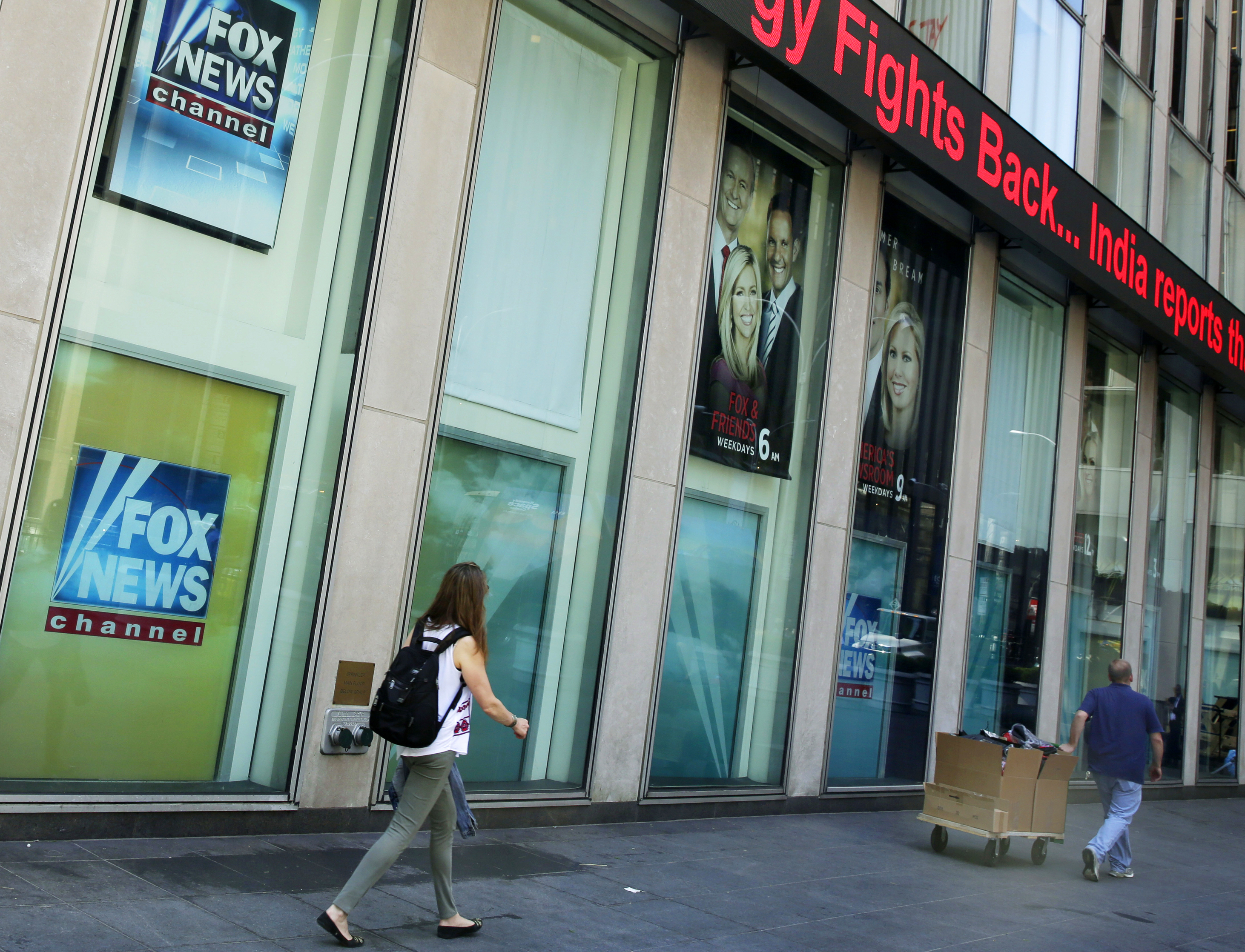 People pass the News Corporation headquarters building and Fox News studios in New York on Aug. 1, 2017. (AP Photo/Richard Drew, File)