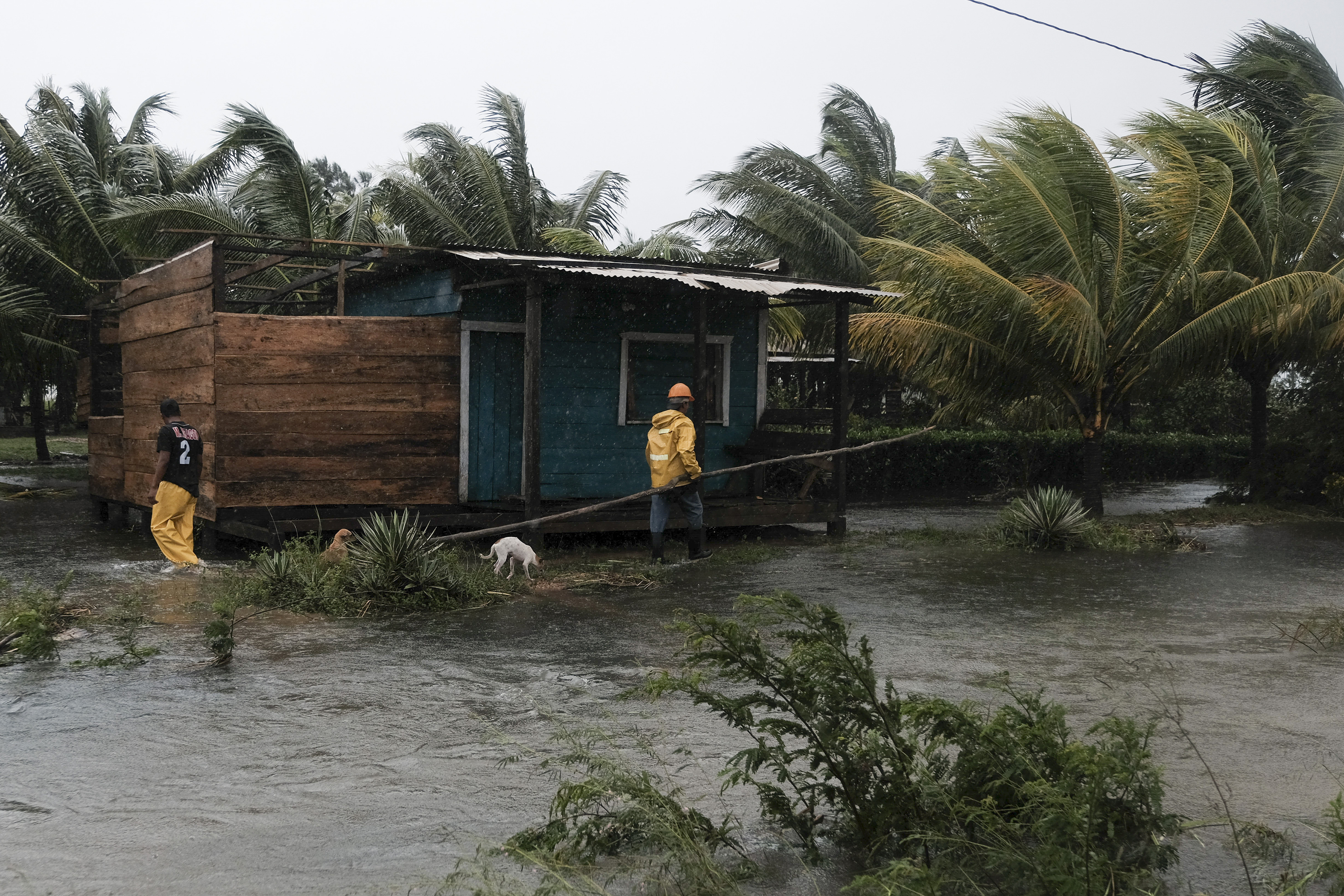 Two men walk around the perimeters of a home surrounded by flood waters brought on by Hurricane Eta in Wawa, Nicaragua on Nov. 3, 2020. (Carlos Herrera/Associated Press)