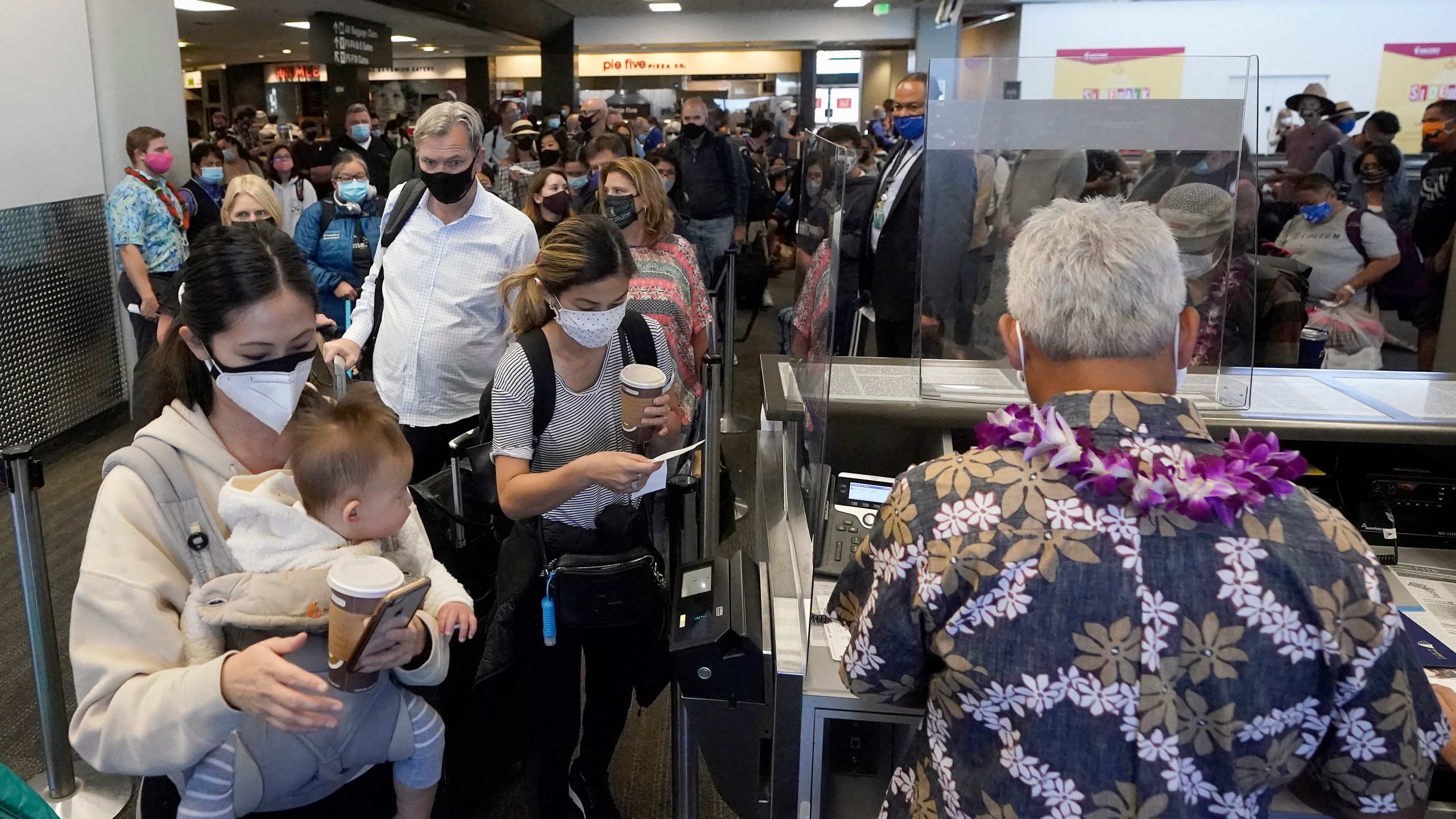 In this Oct. 15, 2020, file photo, United Airlines passengers walk past the gate to board a flight to Hawaii at San Francisco International Airport. (AP Photo/Jeff Chiu, File)