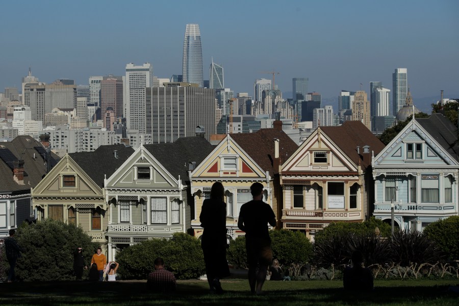 Visitors look toward the "Painted Ladies," a row of historical Victorian homes, in front of the San Francisco skyline from Alamo Square Park on Feb. 26, 2020. (Jeff Chiu / Associated Press)