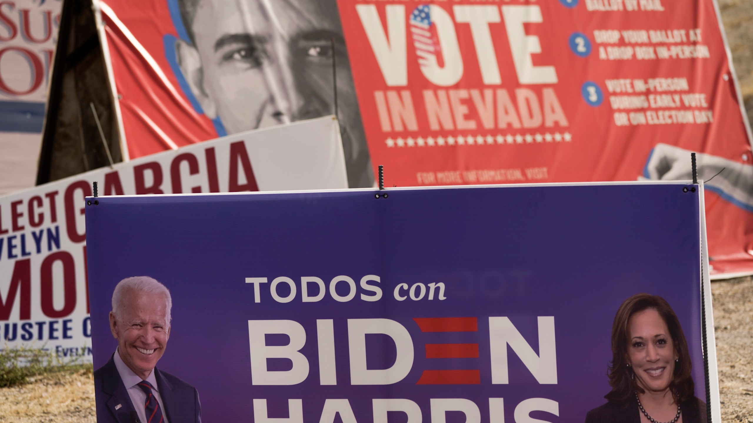 A campaign sign supporting Democratic presidential candidate former Vice President Joe Biden and running mate Kamala Harris stands in front of a vote sign showing former President Barack Obama near the Clark County Election Department in North Las Vegas, Nev., Friday, Nov. 6, 2020. (AP Photo/Jae C. Hong)