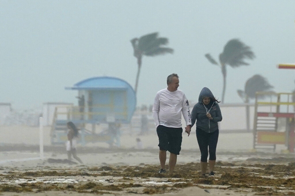 A couple walks along the beach during a downpour, Sunday, Nov. 8, 2020, on Miami Beach, Florida's famed South Beach. (AP Photo/Wilfredo Lee)