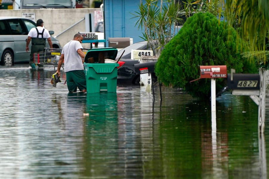 Residents clear debris from a flooded street in the Driftwood Acres Mobile Home Park, in the aftermath of Tropical Storm Eta, Tuesday, Nov. 10, 2020, in Davie, Fla. (AP Photo/Lynne Sladky)