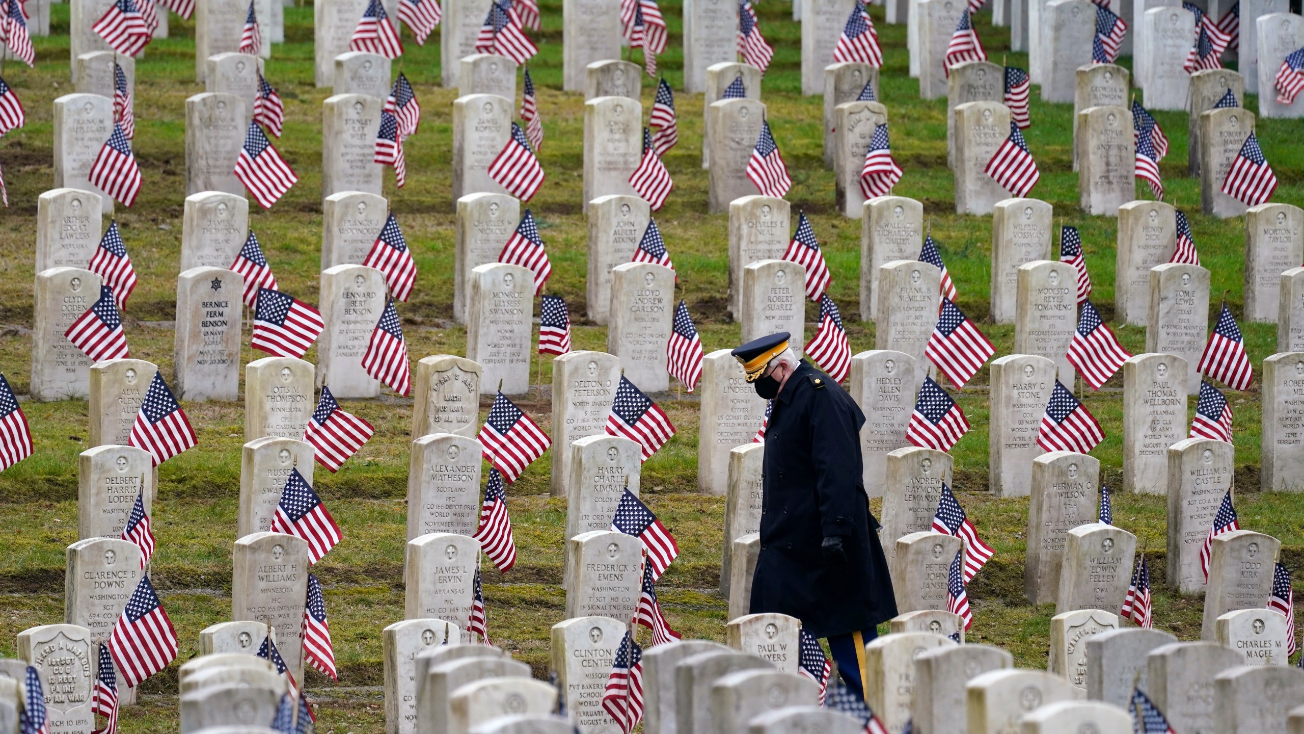 Retired U.S.Army veteran Bill MacCully walks among flag-covered graves in the Veterans Cemetery of Evergreen Washelli Memorial Park on Veterans Day, Nov. 11, 2020, in Seattle. (Elaine Thompson / Associated Press)