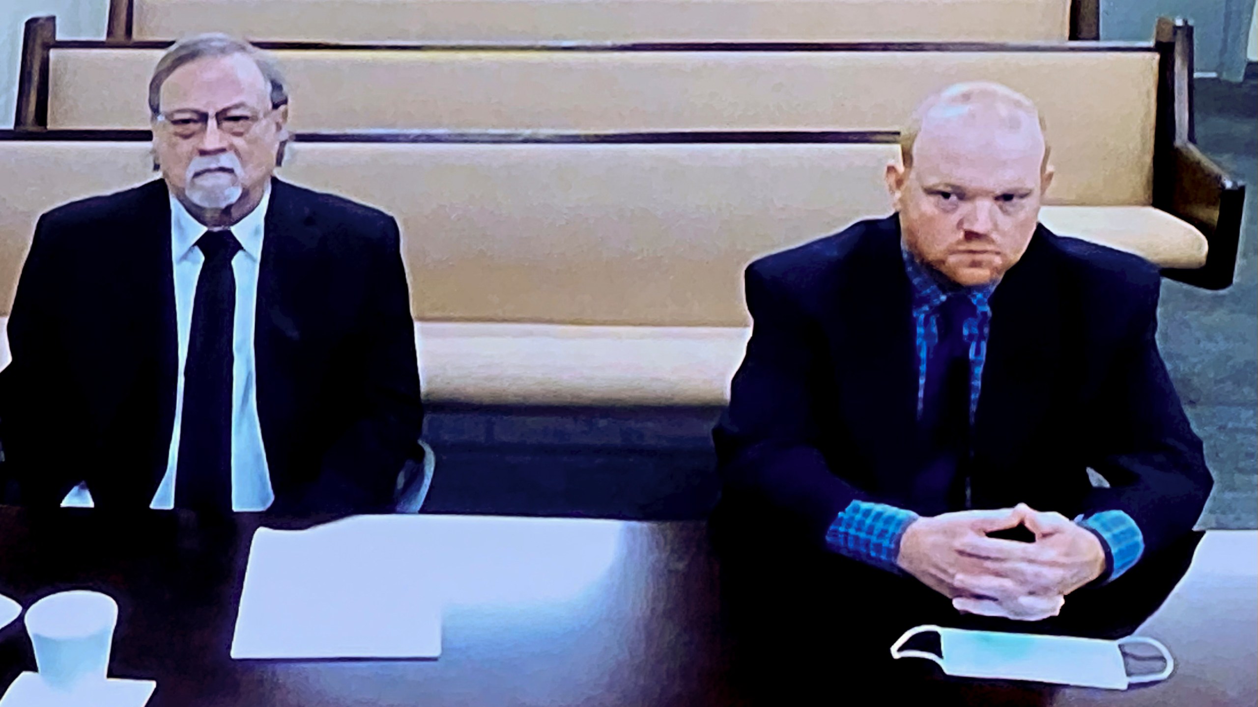 In this image made from video, from left, father and son, Gregory and Travis McMichael, accused in the shooting death of Ahmaud Arbery in Georgia on Feb. 2020, listen via closed circuit tv in the Glynn County Detention center in Brunswick, Ga., on Thursday, Nov. 12, as lawyers argue for bond to be set at the Glynn County courthouse. The McMichaels chased and fatally shot Ahmaud Arbery, a 25-year-old Black man, after they spotted him running in their neighborhood just outside the port city of Brunswick.(AP Photo/Lewis Levine)