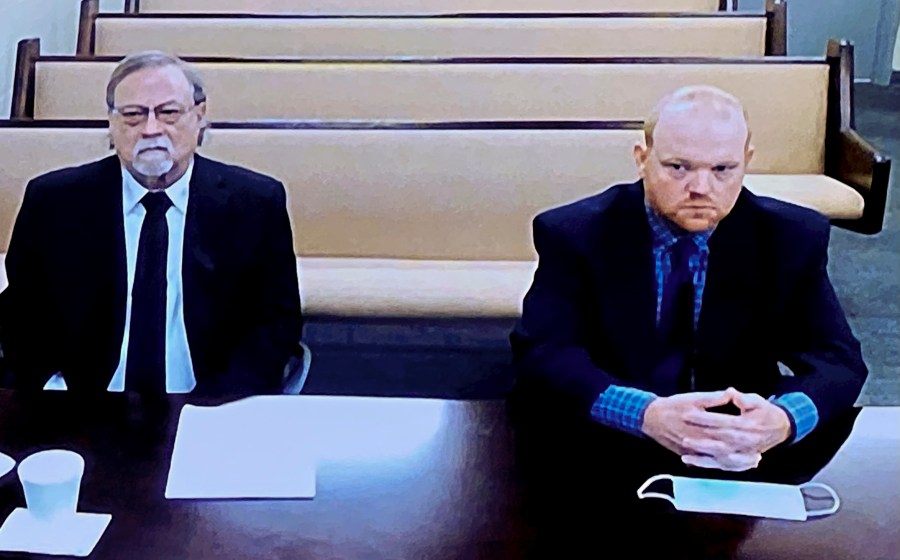 In this image made from video, from left, father and son, Gregory and Travis McMichael, accused in the shooting death of Ahmaud Arbery in Georgia on Feb. 2020, listen via closed circuit tv in the Glynn County Detention center in Brunswick, Ga., on Thursday, Nov. 12, as lawyers argue for bond to be set at the Glynn County courthouse. The McMichaels chased and fatally shot Ahmaud Arbery, a 25-year-old Black man, after they spotted him running in their neighborhood just outside the port city of Brunswick.(AP Photo/Lewis Levine)