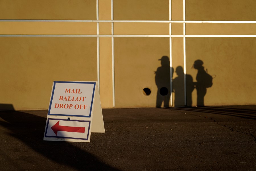 In this Nov. 3, 2020, file photo people wait outside of a polling place on Election Day in Las Vegas. Nevada election law stipulates that in order to register to vote, an individual must have been a resident for 30 days preceding an election, but does not specify how long an already registered voter must be physically present in the state in order to participate in an election. (AP Photo/John Locher, File)