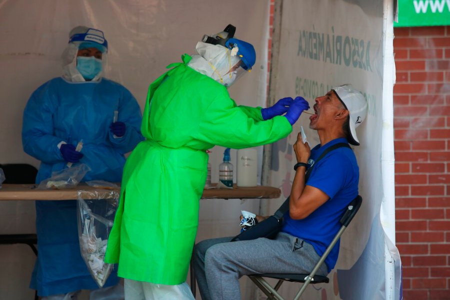 A healthcare worker tests a person for the new coronavirus inside a diagnostic tent in Mexico City, Saturday, Nov. 14, 2020. (AP Photo/Ginnette Riquelme)