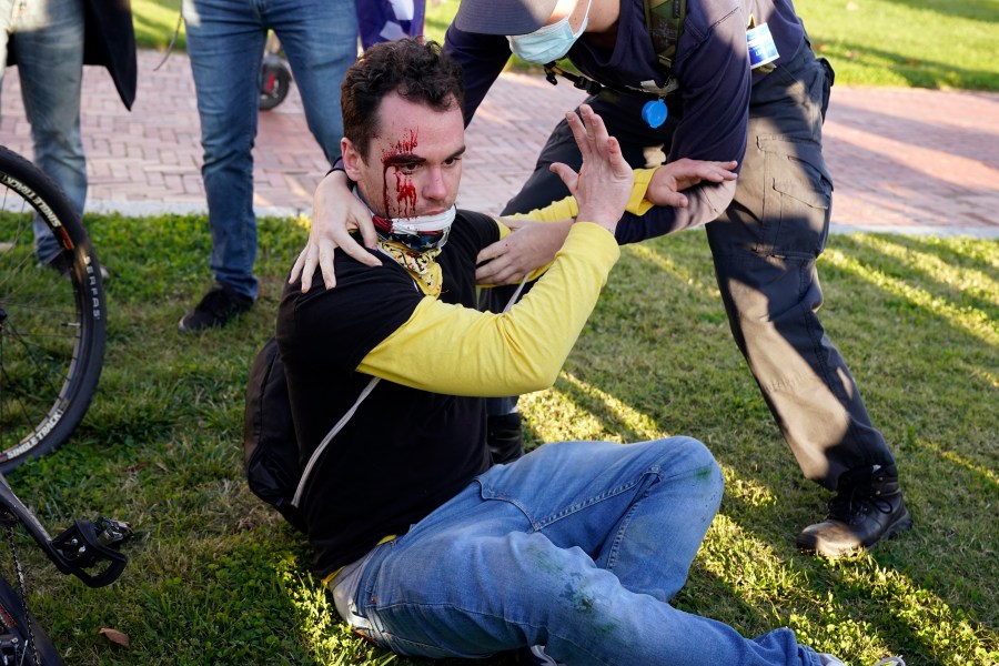 A counter-protester helps a supporter of President Donald Trump who was injured after he was attacked during a pro-Trump rally on Nov. 14, 2020, in Washington. (AP Photo/Jacquelyn Martin)