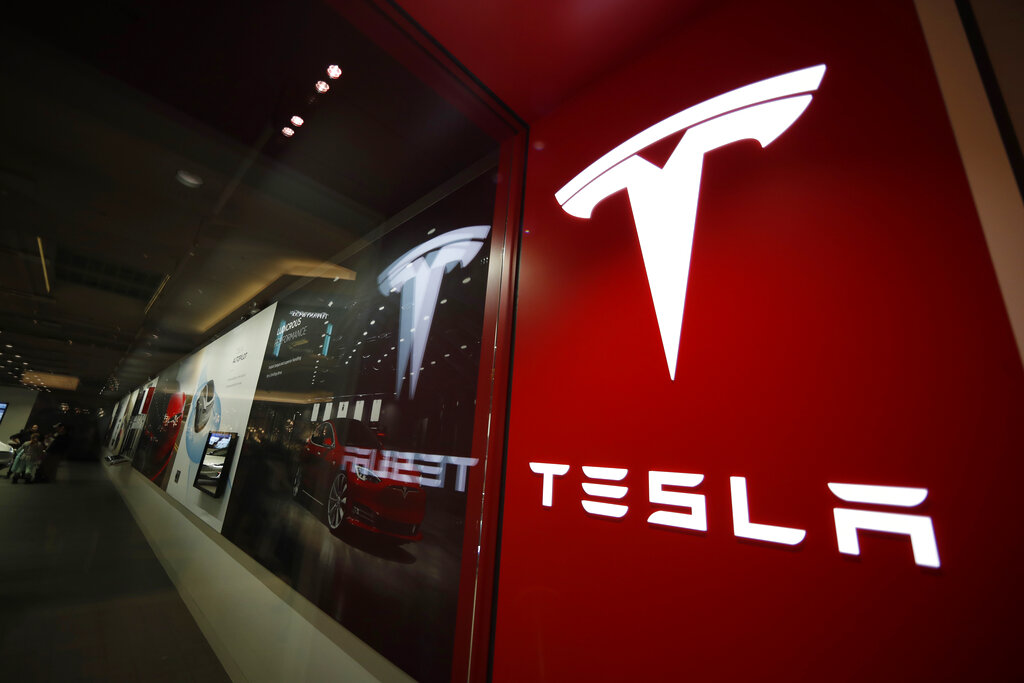 In this Feb. 9, 2019, file photo, a sign bearing the company logo stands outside a Tesla store in Cherry Creek Mall in Denver. (AP Photo/David Zalubowski, File)