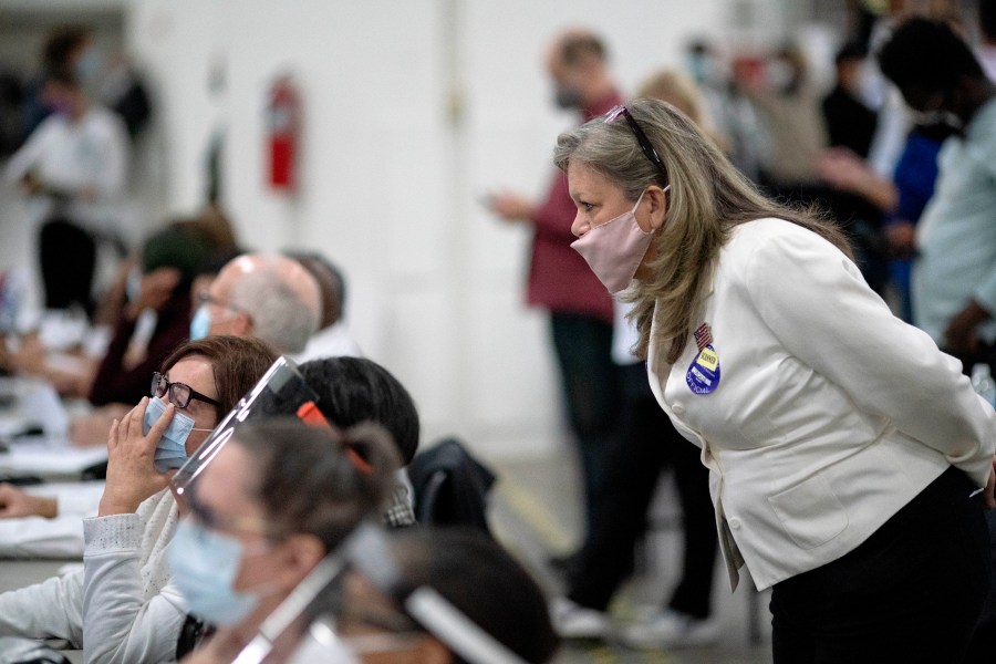 In this Nov. 4, 2020, file photo, a Republican election challenger at right watches over election inspectors as they examine a ballot as votes are counted into the early morning hours at the central counting board in Detroit. (AP Photo/David Goldman, File)