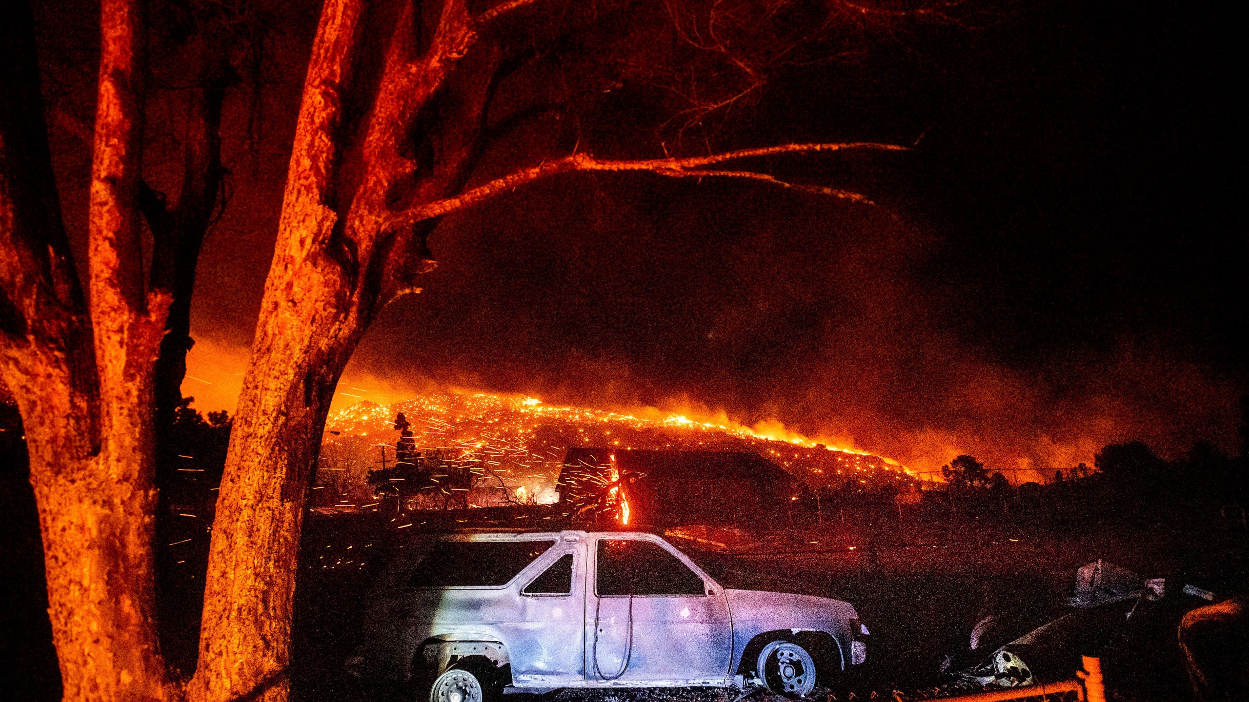 A scorched vehicle rests in a yard as the Mountain View Fire tears through the Walker community in Mono County, on Tuesday, Nov. 17, 2020. (AP Photo/Noah Berger)