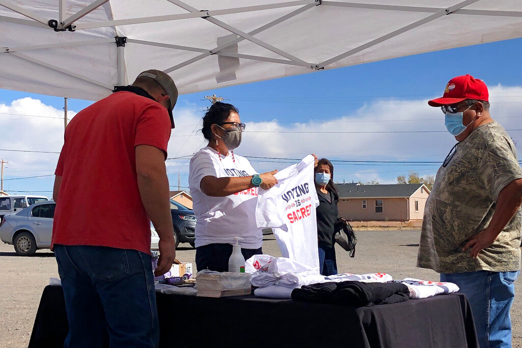 This photo provided by Carol Davis shows Cherilyn Yazzie speaking to a voter on Nov. 3, 2020, in the Navajo community of Dilkon in northeastern Arizona. (Carol Davis via AP)