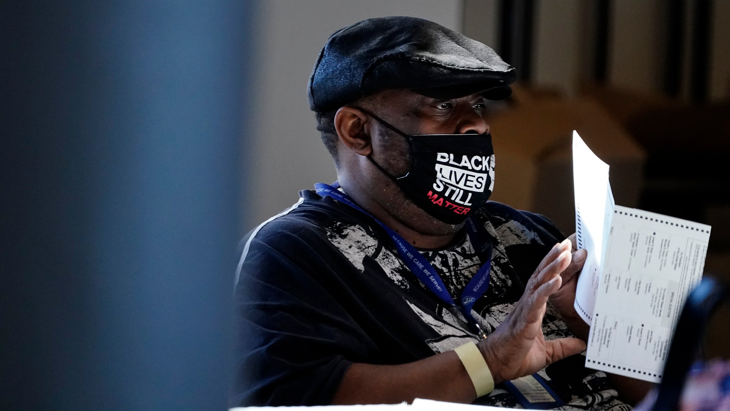 In this Nov. 4, 2020, file photo, an election worker holds a ballot as vote counting in the general election continues at State Farm Arena in Atlanta. President-elect Joe Biden won in Michigan, Wisconsin, Pennsylvania and Georgia because of Black voters, many of them concentrated in big cities. (AP Photo/Brynn Anderson, File)