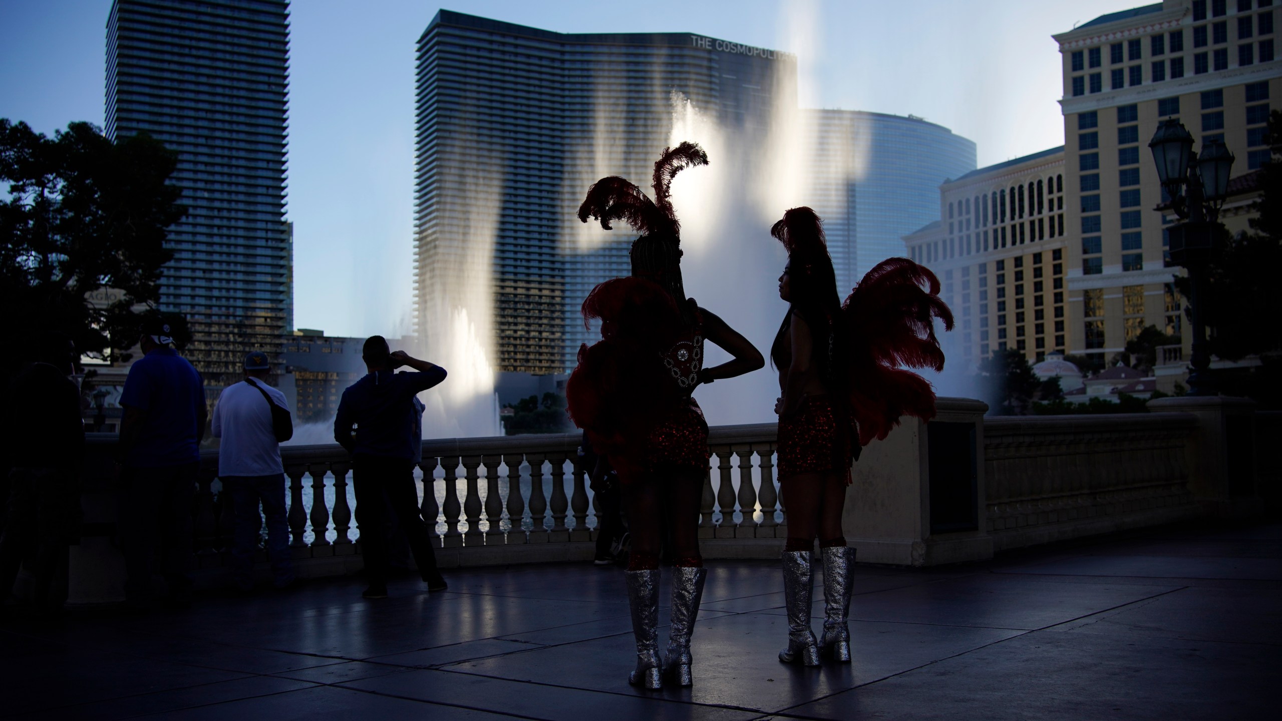 People dressed as showgirls stand along the Las Vegas Strip, Thursday, Nov. 19, 2020, in Las Vegas. As the coronavirus surges to record levels in Nevada, the governor has implored residents to stay home. But Democrat Steve Sisolak has also encouraged out-of-state visitors, the lifeblood of Nevada's limping economy, to come to his state and spend money in Las Vegas. (AP Photo/John Locher)