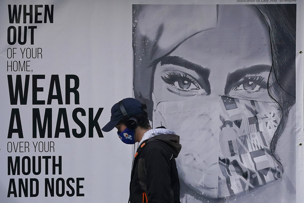 A pedestrian walks past a sign advising mask-wearing during the coronavirus outbreak in San Francisco on Nov. 21, 2020. (AP Photo/Jeff Chiu)