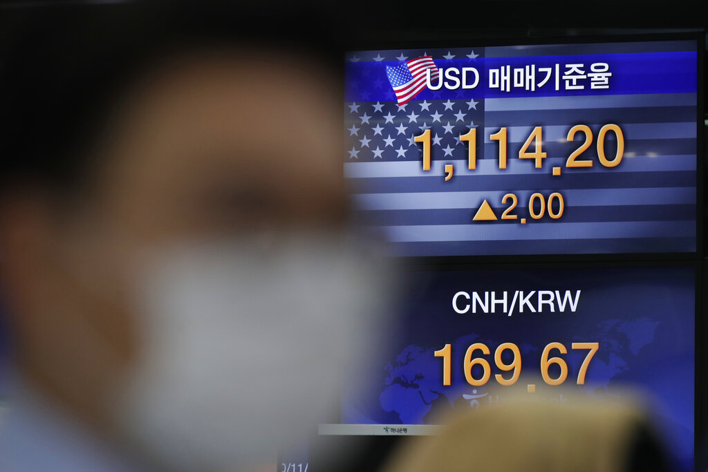 A currency trader watches computer monitors near screens showing the foreign exchange rates at the foreign exchange dealing room in Seoul, South Korea, Monday, Nov. 23, 2020. (AP Photo/Lee Jin-man)