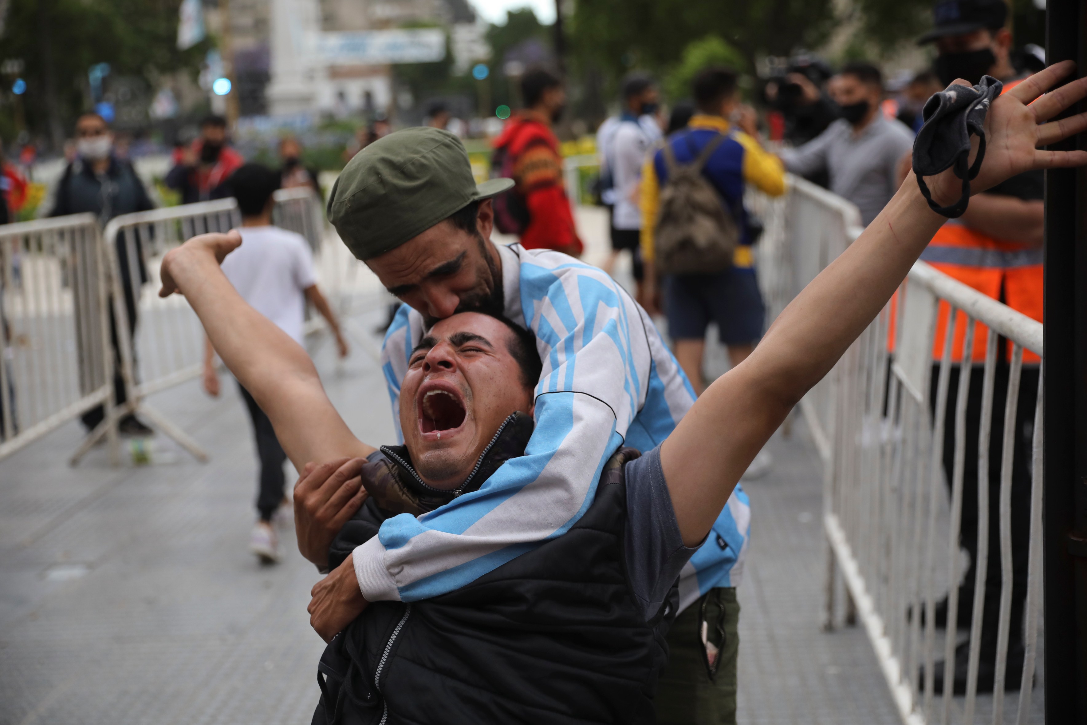 Mourners embrace as they wait to see Diego Maradona lying in state outside the presidential palace in Buenos Aires, Argentina, on Nov. 26, 2020. (Rodrigo Abd / Associated Press)