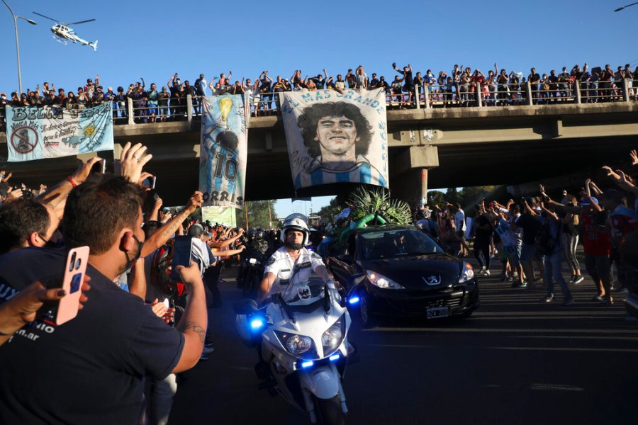 Mourning fans wave from an overpass at the caravan carrying the remains of Diego Maradona to his resting place in Buenos Aires, Argentina, Thursday, Nov. 26, 2020. (AP Photo/Rodrigo Abd)