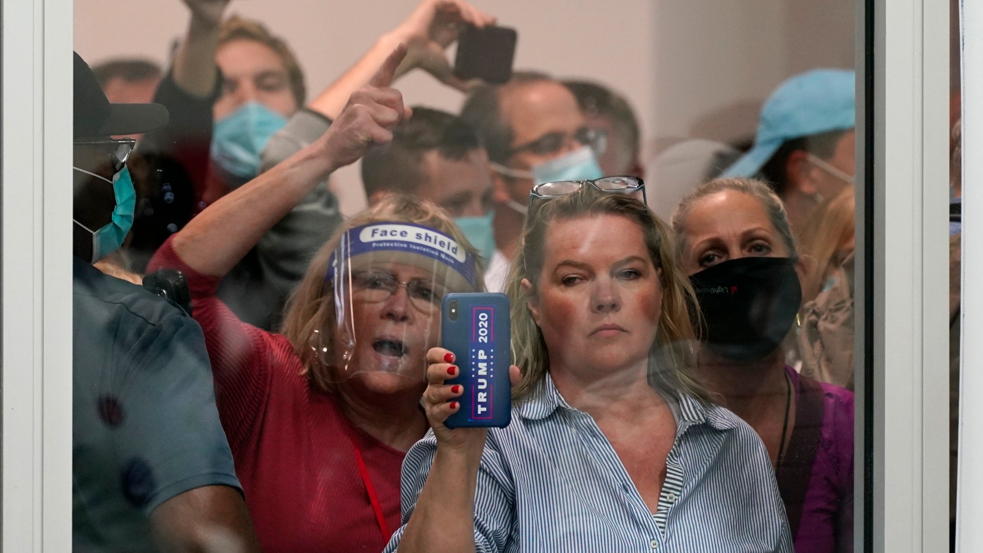 People wanting to be election challengers yell as they look through the windows of the central counting board as police were helping to keep additional challengers from entering due to overcrowding, Wednesday, Nov. 4, 2020, in Detroit. (AP Photo/Carlos Osorio)