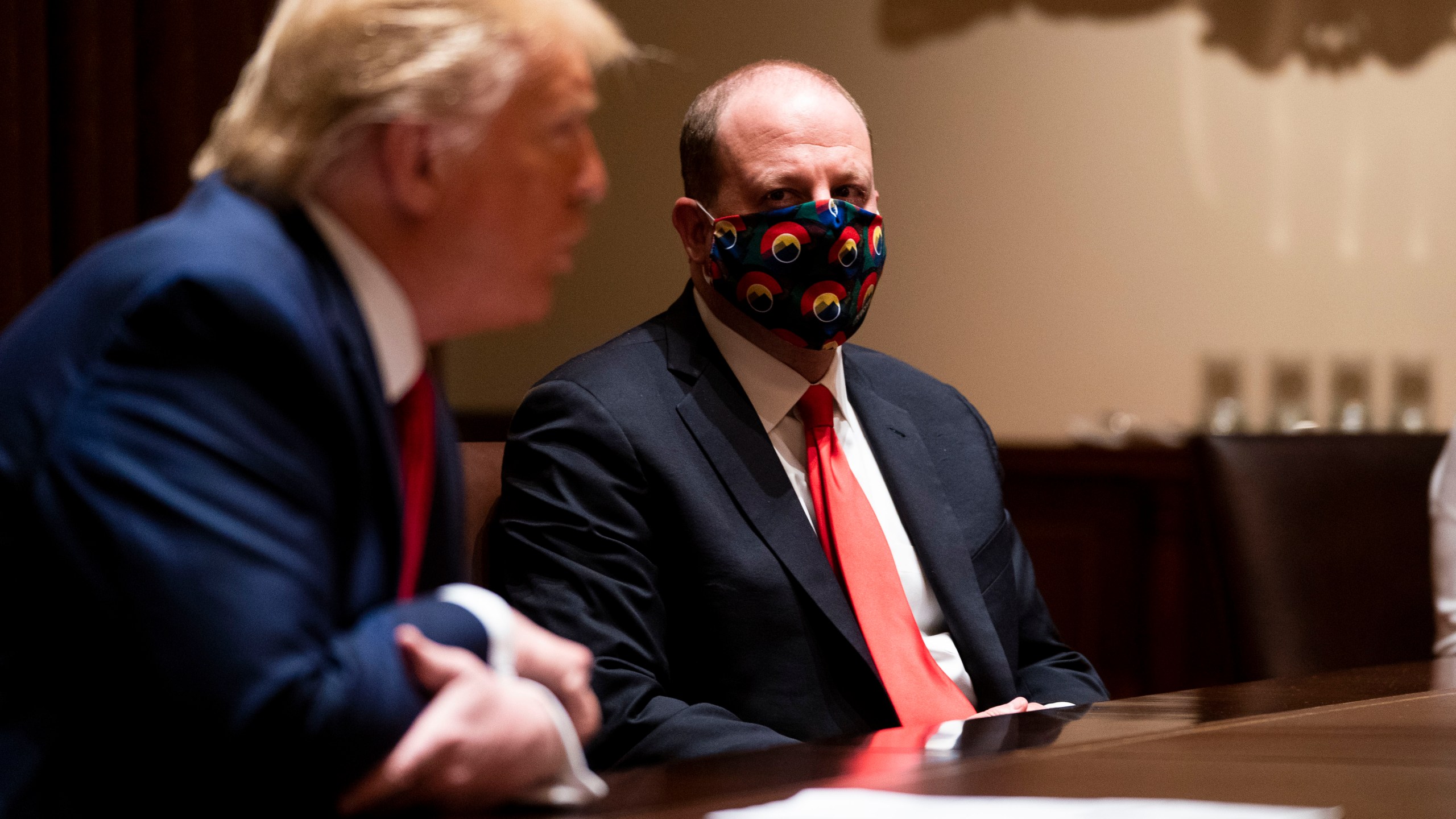 Colorado Governor Jared Polis wears a face mask as U.S. President Donald Trump makes remarks during a meeting in the Cabinet Room of the White House, May 13, 2020 in Washington, DC. (Photo by Doug Mills-Pool/Getty Images)