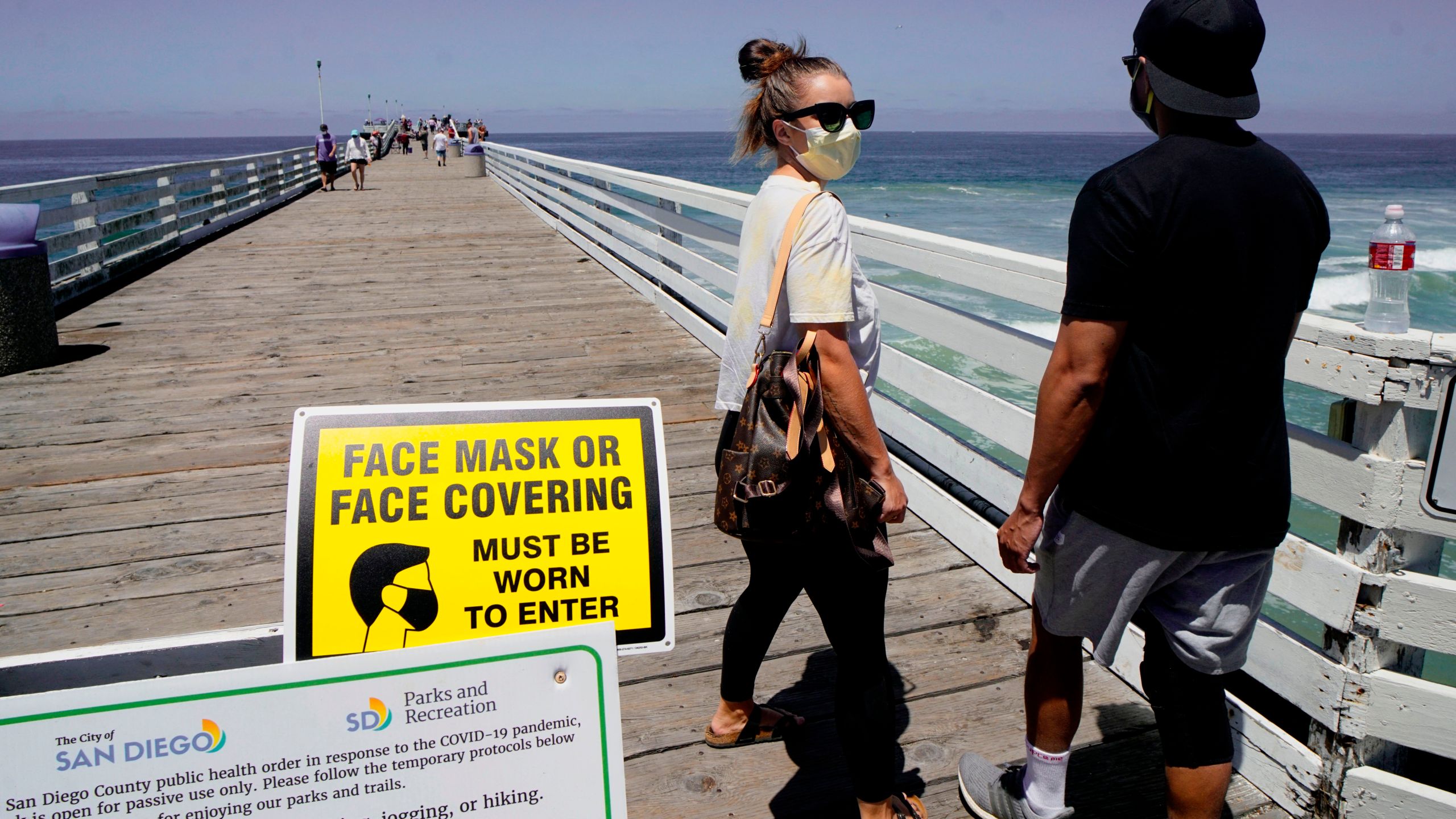 Beachgoers walk out onto the Pacific Beach Pier in San Diego on Saturday, July 4, 2020, amid the coronavirus pandemic. (SANDY HUFFAKER/AFP via Getty Images)