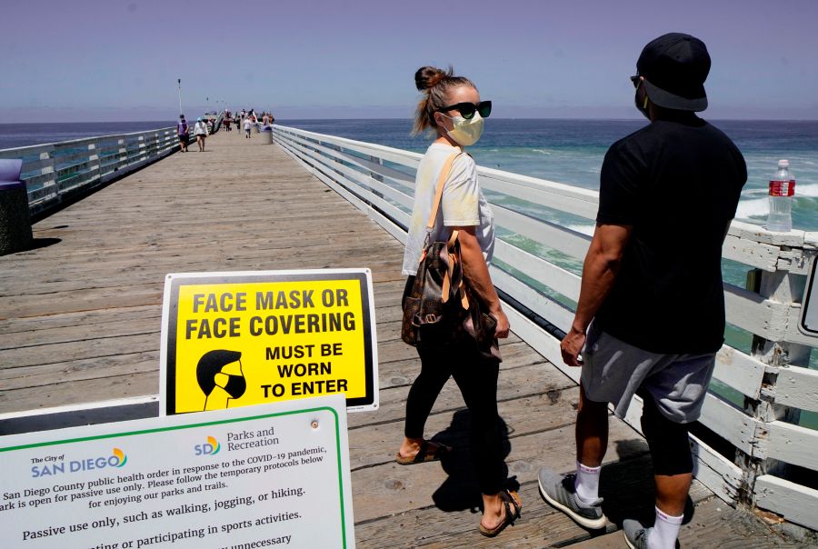 Beachgoers walk out onto the Pacific Beach Pier in San Diego on Saturday, July 4, 2020, amid the coronavirus pandemic. (SANDY HUFFAKER/AFP via Getty Images)