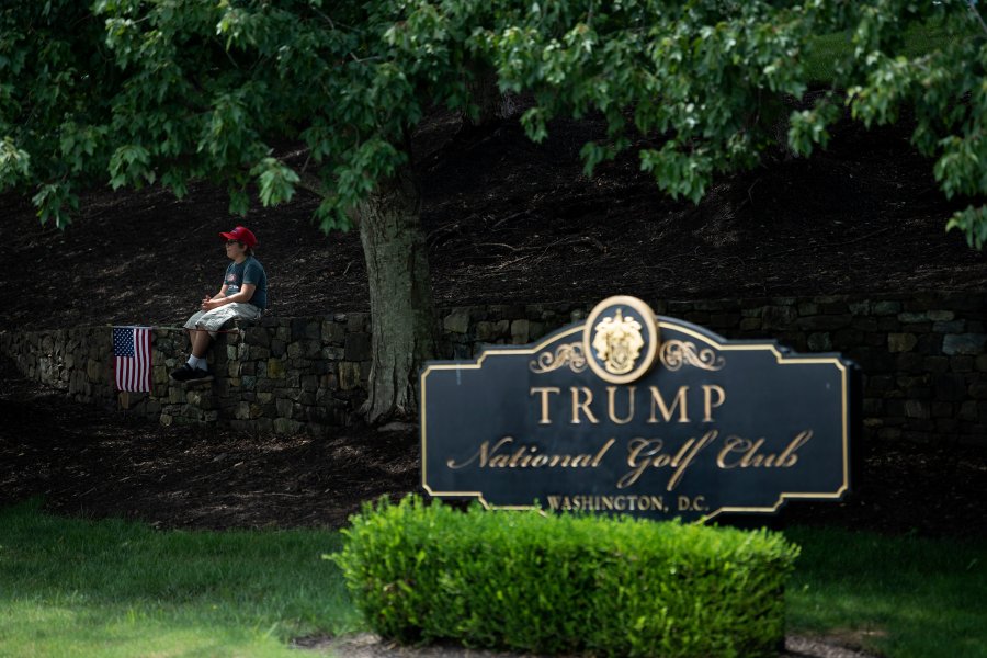 A boy sits on a wall as protesters and supporters of Donald Trump gather outside the Trump National Golf Club as the president golfs at the club on Aug.2, 2020, in Sterling, Virginia. (Brendan Smialowski/AFP via Getty Images)