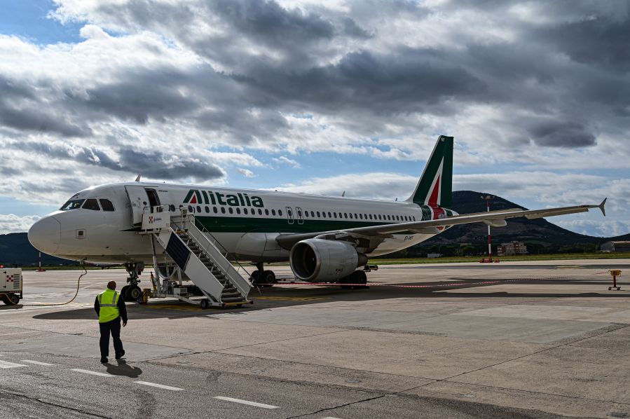 An airport employee walks towards an Alitalia plane just arrived at the Alghero-Fertilia "Riviera del Corallo" Airport on October 6, 2020. (Miguel Medina/AFP via Getty Images)