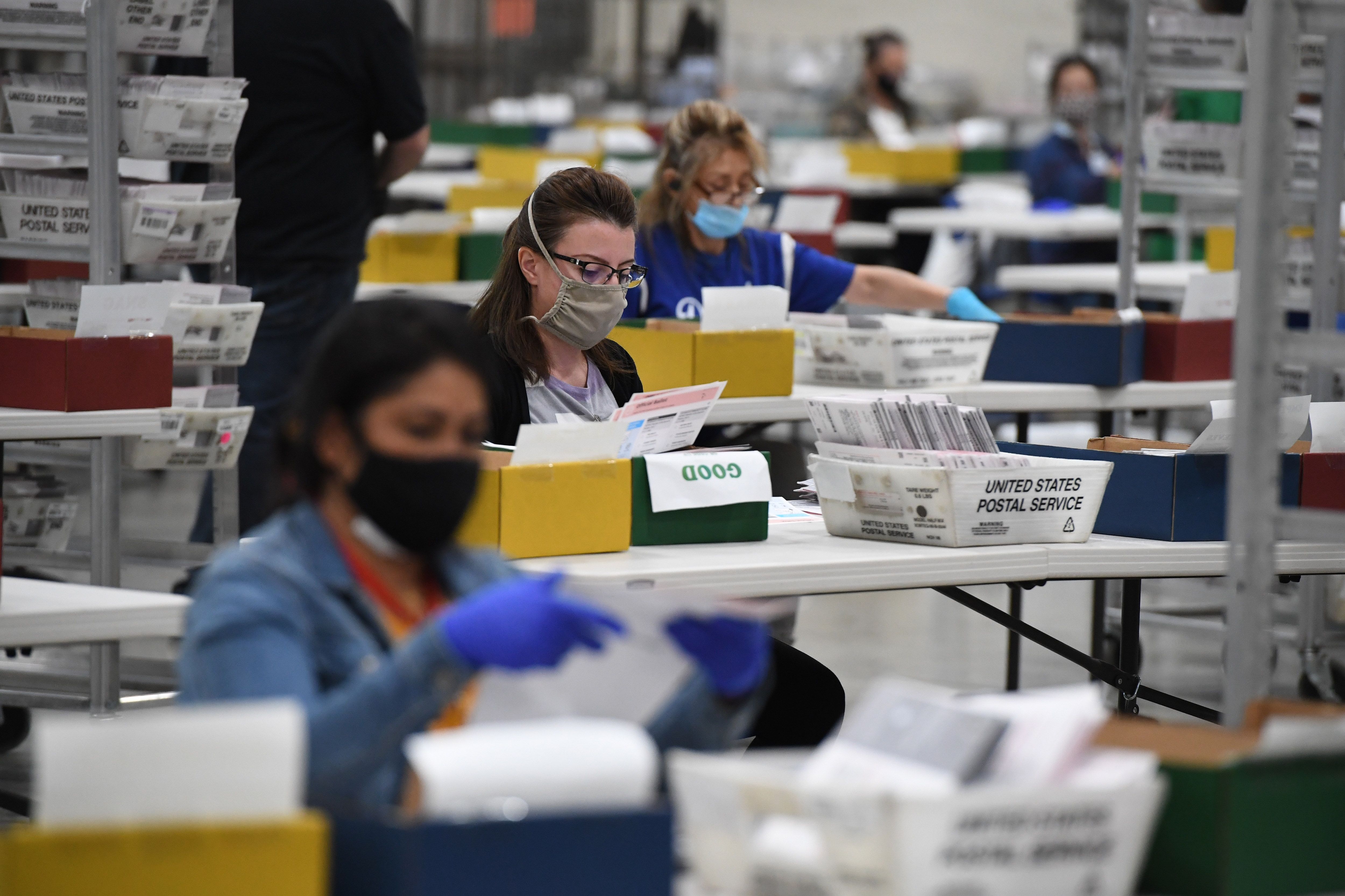 Election workers extract mail-in ballots from their envelopes and examine the ballot for irregularities at the Los Angeles County Registrar Recorders' mail-in ballot processing center at the Pomona Fairplex in Pomona on Oct. 28, 2020. (ROBYN BECK/AFP via Getty Images)