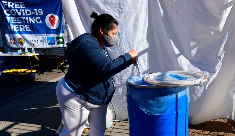 A woman, who just tested herself, places the bag with her mouth swab into a container for testing at a pop-up Covid-19 Test site in Los Angeles, California on October 29, 2020, where the testing is walk-up only with no appointments necessary and results in 48 hours. - (Frederic J. Brown/AFP via Getty Images)