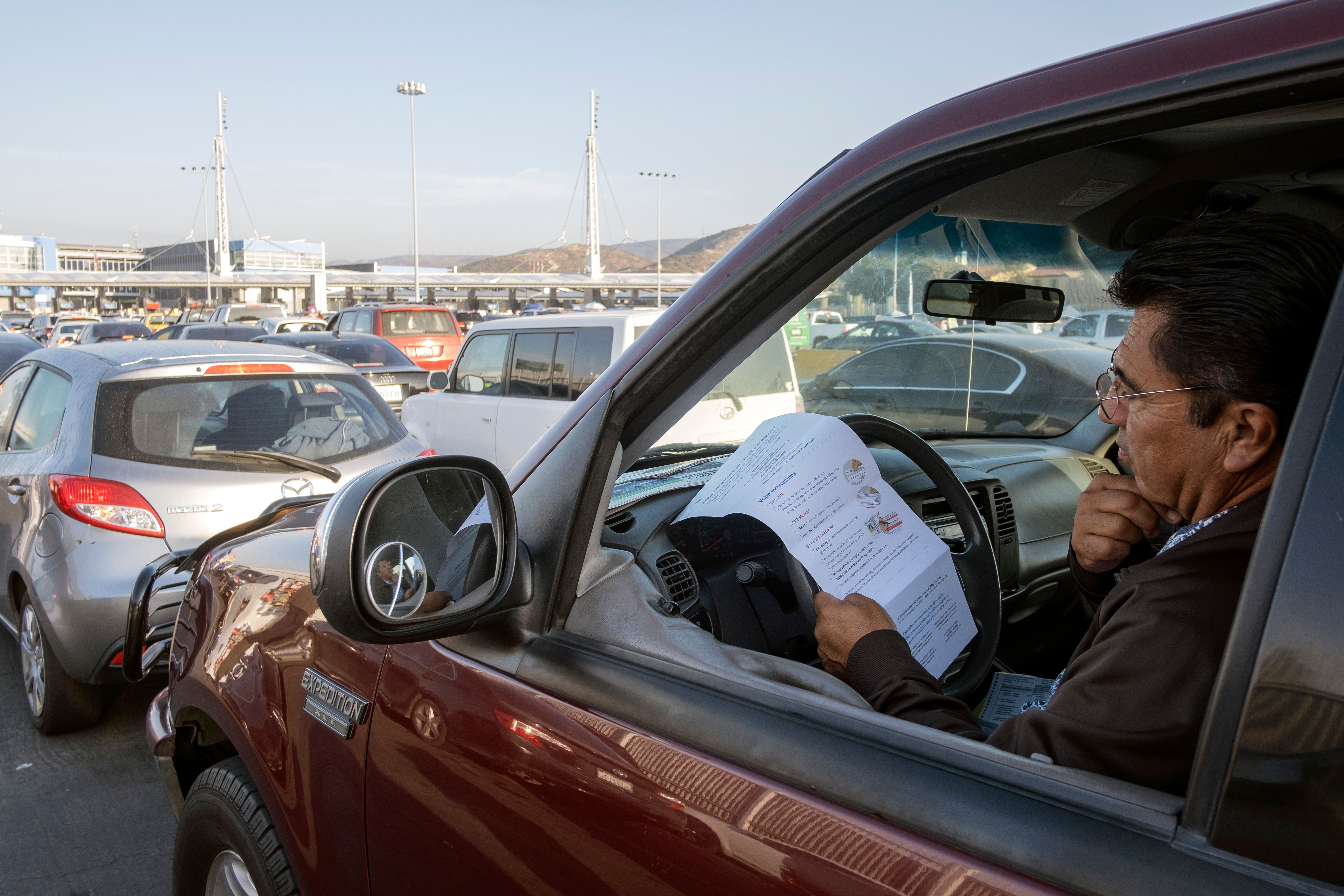 U.S. citizen Rafael Millan reads ballot instructions before crossing the border to deposit his vote, at the U.S.-Mexico border in San Ysidro Crossing Port in Tijuana on Nov. 3, 2020 (Guillermo Arias/AFP via Getty Images)