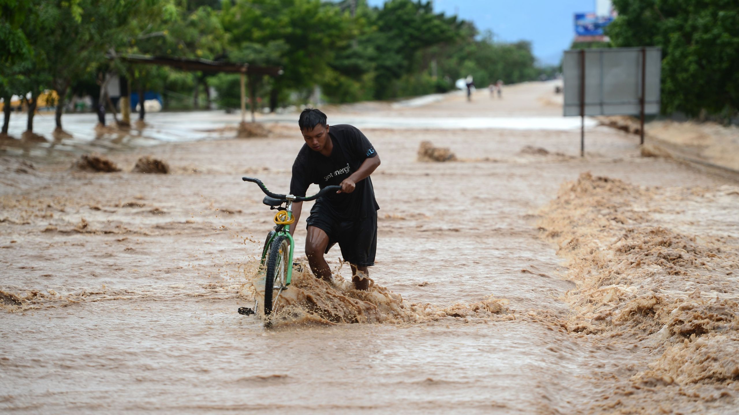 A man wades with his bike in a flooded street due to the heavy rains caused by Hurricane Eta, now degraded to a tropical storm, in El Progreso, department of Yoro, 260 kms north of Tegucigalpa, on Nov. 5, 2020. (Orlando SIERRA / AFP via Getty Images)