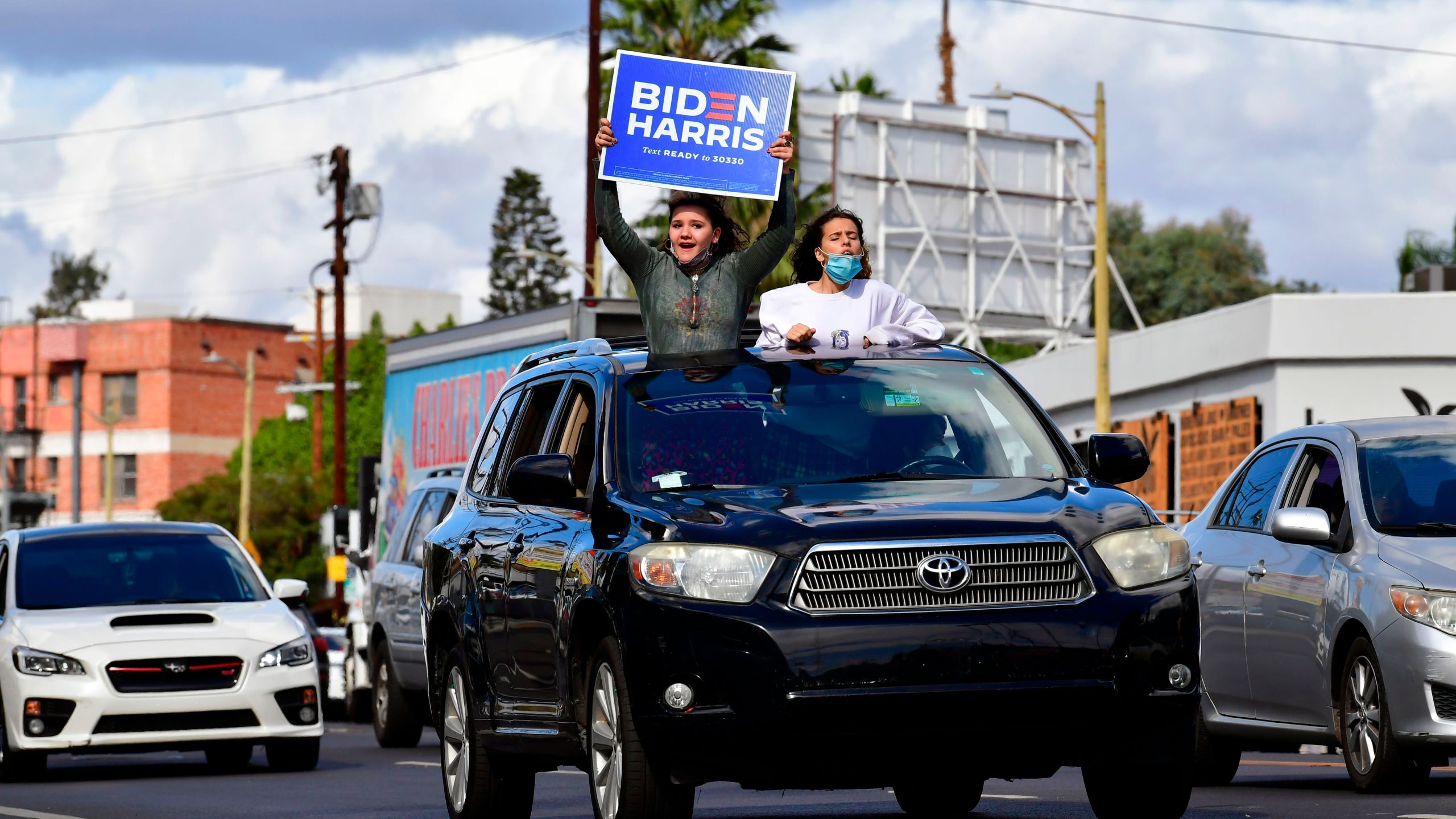 Young supporters cheer from their car holding a Biden-Harris placard as people take to the streets in Los Angeles on Nov.cn 7, 2020 to celebrate Joe Biden and the Democratic Party's victory in the 2020 US presidential elections. (FREDERIC J. BROWN/AFP via Getty Images)