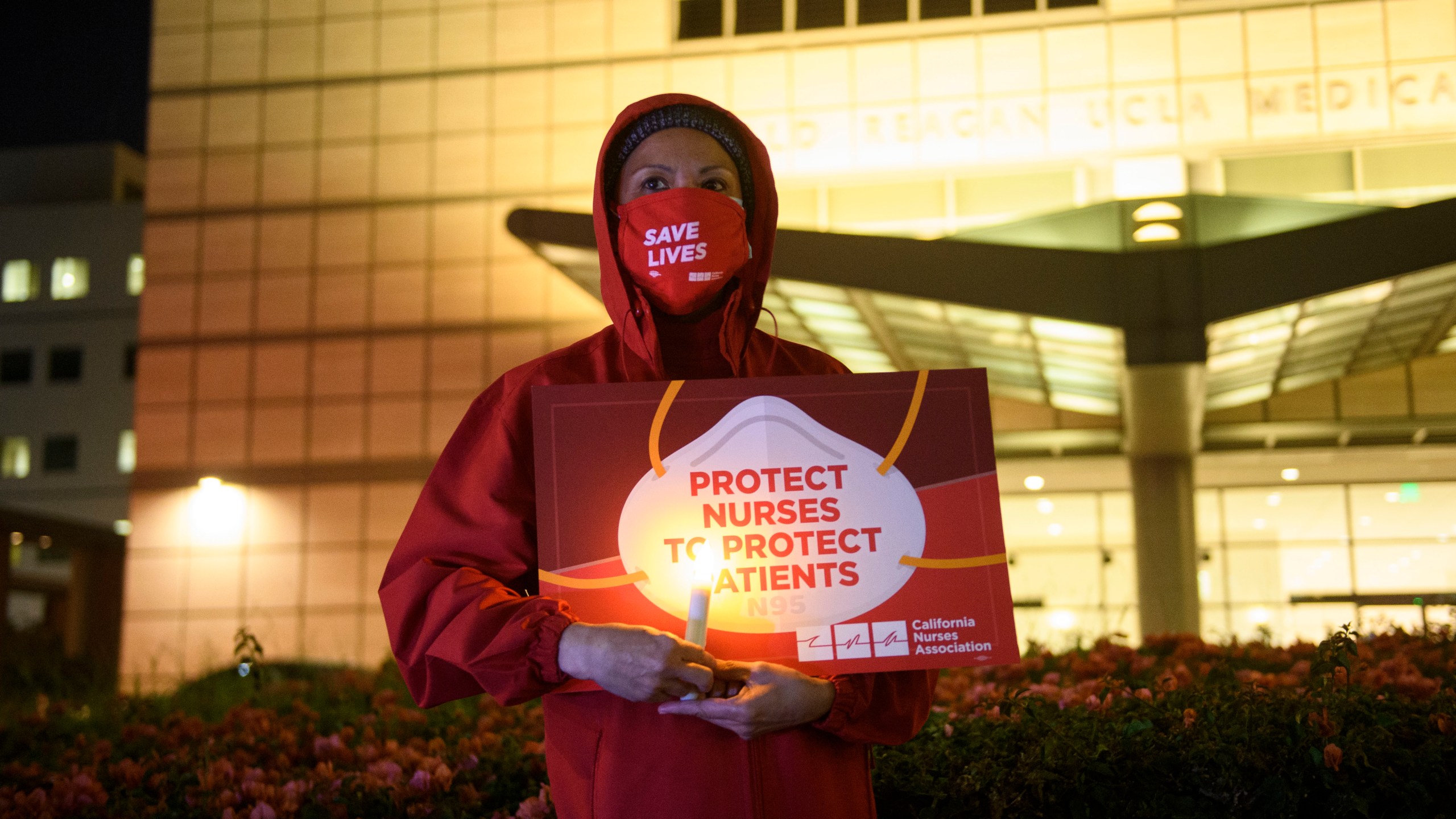 A nurse holds a candle during a vigil for health care workers who died from COVID-19 organized by California Nurses United outside of UCLA Medical Center in Los Angeles. (PATRICK T. FALLON/AFP via Getty Images)